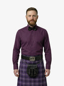 Man wearing a purple shirt, bow tie, and tartan kilt on a white background