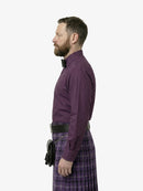 Man wearing a purple shirt and plaid kilt on a white background