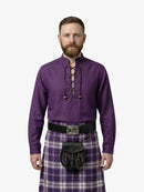 Man wearing a purple shirt and tartan kilt on a white background