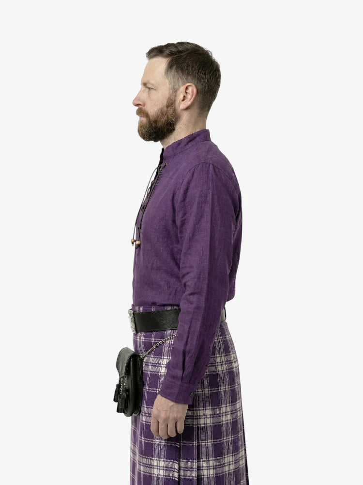 Man wearing a purple shirt and plaid pants on a white background