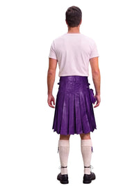 A man shown from the back wearing a purple pleated kilt, a light pink t-shirt, white knee-high socks, and black shoes, isolated on a white background.
