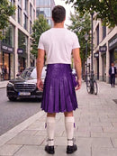 A man standing on a city sidewalk, viewed from behind, wearing a white t-shirt, a purple pleated leather kilt, white knee-high socks, and black shoes. A black Mercedes-Benz car is parked on the street to his left, with trees and storefronts in the background.