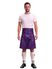A man modeling a purple faux-leather kilt with a front pouch and silver buckle, paired with a white t-shirt, cream knee-high socks, and black lace-up shoes, against a plain white background.