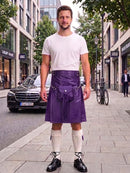A man stands on a city sidewalk wearing a purple leather kilt with a white t-shirt, white knee-high socks, and black shoes. The background shows a street with buildings, a black Mercedes-Benz car, and a bicycle.