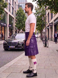 A man standing on a city sidewalk wearing a purple leather kilt, white t-shirt, white socks, and black shoes, with a street scene and parked cars in the background.