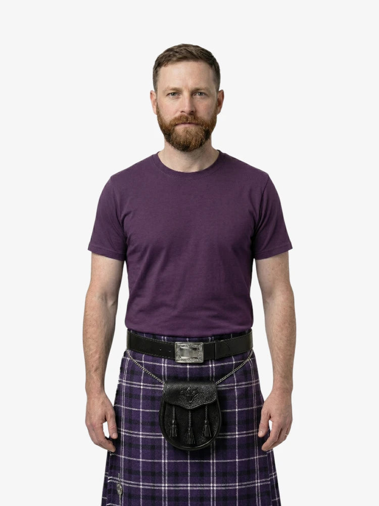 Man wearing a purple t-shirt and tartan kilt on a white background