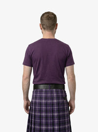 Man wearing a purple t-shirt and plaid kilt on a white background