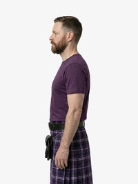 Man wearing a purple t-shirt and plaid kilt on a white background
