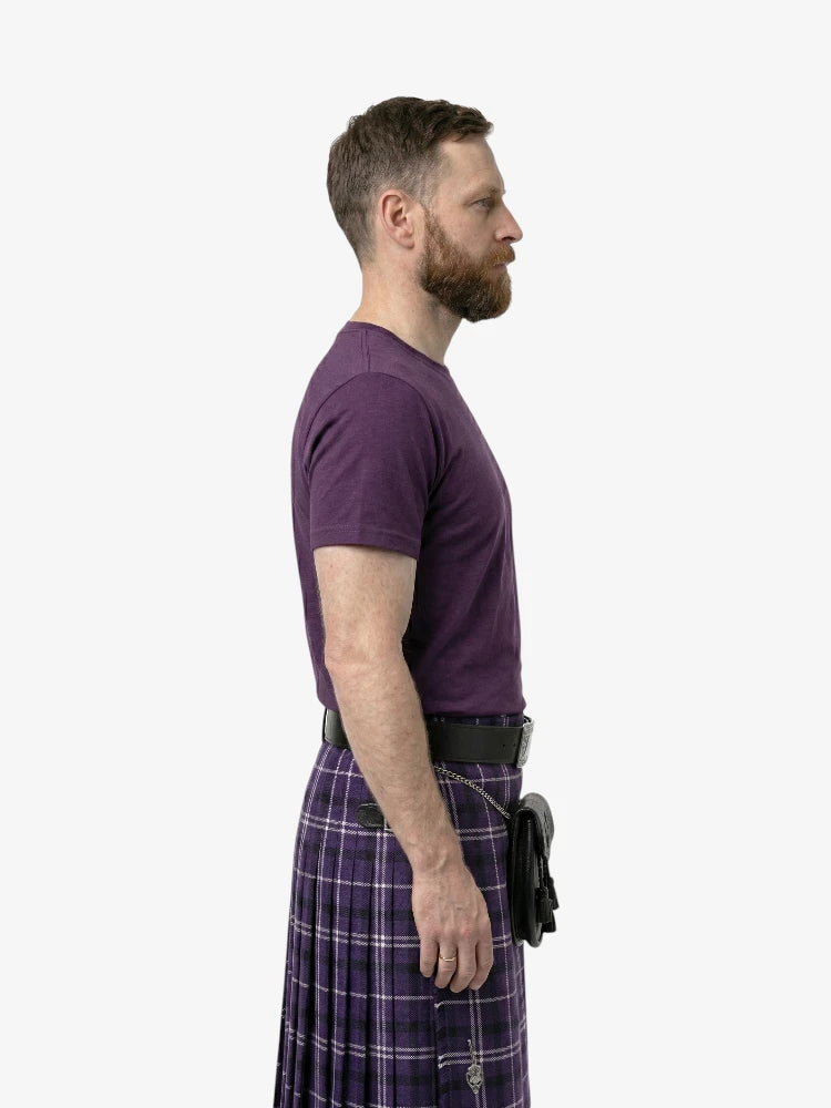 Man wearing a purple t-shirt and plaid kilt on a white background