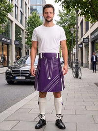 A man stands on a city sidewalk wearing a purple kilt with white geometric line details, a white t-shirt, white knee-high socks, and black shoes. Buildings, trees, and a parked black car are visible in the background.