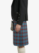 Person wearing a black jacket and blue plaid kilt on a white background