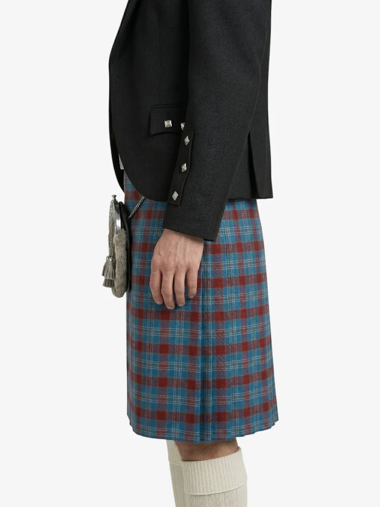 Person wearing a black jacket and blue plaid kilt on a white background