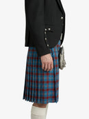 Person wearing a black blazer and blue plaid kilt on a white background