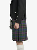Person wearing a black blazer and plaid kilt on a white background