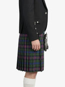 Person wearing a black blazer and plaid kilt on a white background