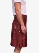 A side view of a person wearing a dark red leather kilt with pleated detailing and flap pockets with silver-tone snaps, paired with a white t-shirt, against a plain white background.