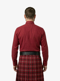 Man wearing a red shirt and tartan kilt on a white background