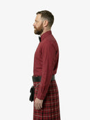 Man wearing a red shirt and tartan kilt on a white background