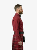 Man wearing a red shirt and tartan kilt on a white background