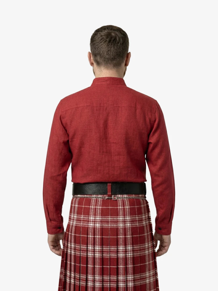 Man wearing a red shirt and plaid kilt on a white background