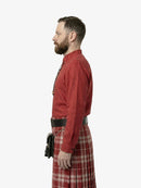 Man wearing a red shirt and tartan kilt on a white background