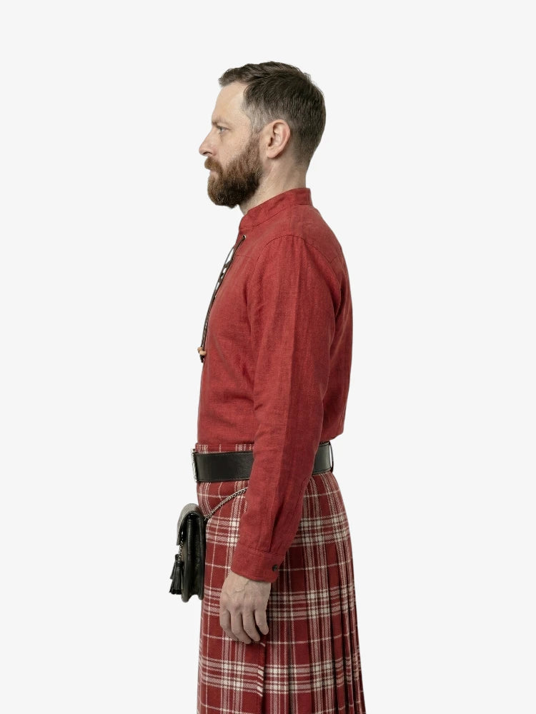 Man wearing a red shirt and tartan kilt on a white background