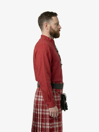Man wearing a red shirt and plaid kilt on a white background