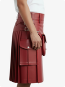Red pleated skirt with silver buckles worn by a person on a white background