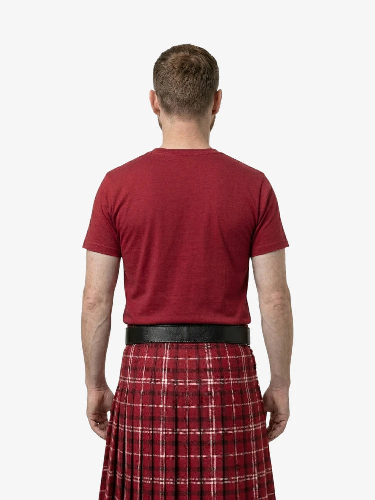 Man wearing a red t-shirt and red plaid kilt on a white background
