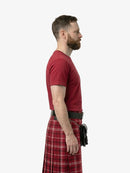 Man wearing a red t-shirt and plaid kilt on a white background
