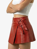 Red leather skirt with a tie waist worn by a person on a white background