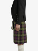 Person wearing a black jacket and green plaid skirt on a white background