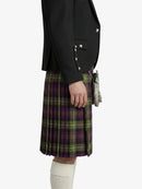 Person wearing a black jacket and green plaid kilt on a white background