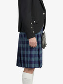 Person wearing a black jacket and blue plaid kilt on a white background