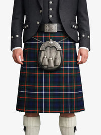 Person wearing a Scottish kilt with a tartan pattern on a white background