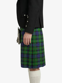 Person wearing a black jacket and green plaid kilt on a white background