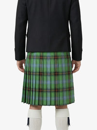 Person wearing a black jacket and green plaid kilt on a white background