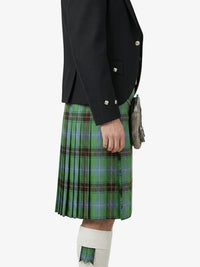 Person wearing a black jacket and green plaid kilt on a white background