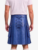 A person shown from the back wearing a royal blue pleated leather kilt with a lace-up back and side cargo pockets, paired with a light pink t-shirt and cream socks.