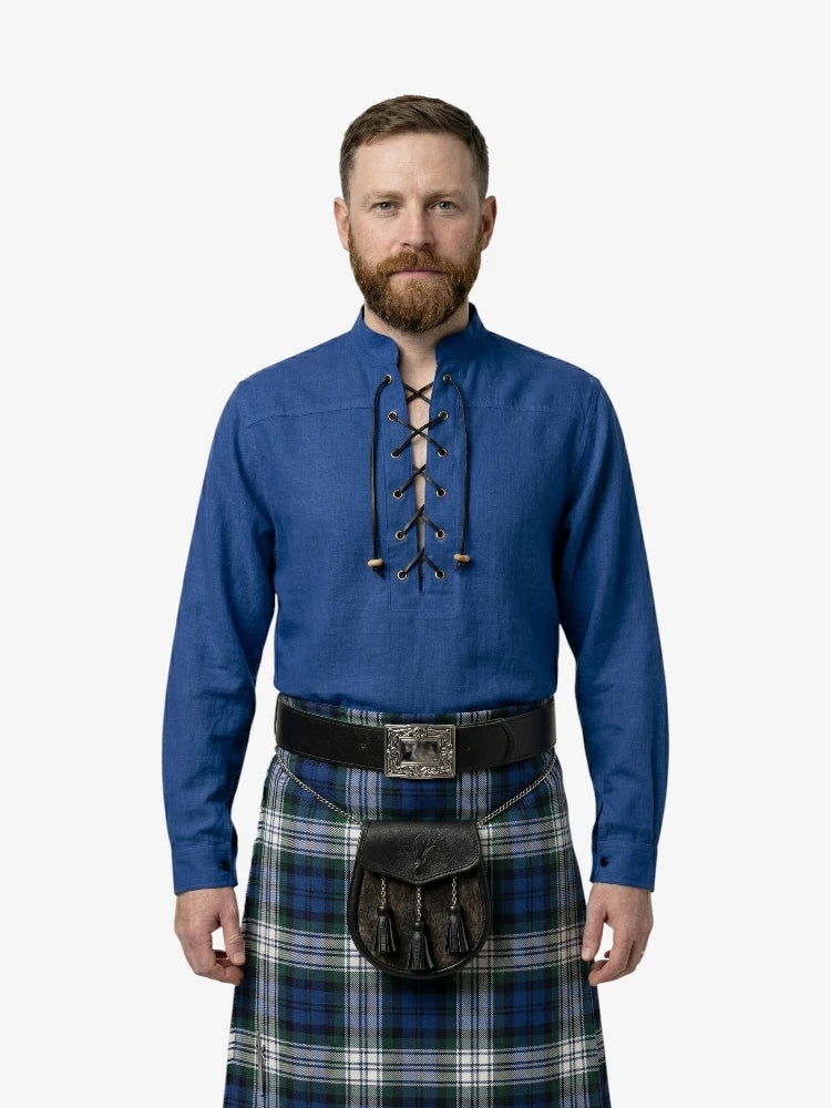 Man wearing a blue shirt with lace-up front and a plaid kilt on a white background