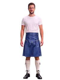 A man modeling a blue leather kilt with a matching belt and silver buckle, paired with a white t-shirt, white knee-high socks, and black lace-up boots, against a solid white background.