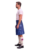 A man shown in profile wearing a blue leather kilt, a white t-shirt, white socks, and black shoes, photographed against a plain white background.