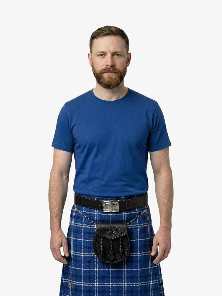 Man wearing a blue t-shirt and blue plaid kilt on a white background
