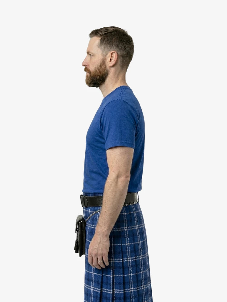Man wearing a blue t-shirt and plaid kilt on a white background