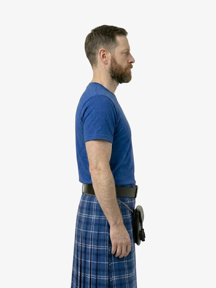 Man wearing a blue shirt and plaid kilt on a white background