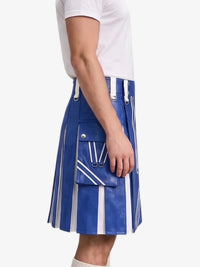 A person wearing a blue pleated leather kilt with white vertical stripes, diagonal stripe details, and a large front flap pocket with silver-tone hardware, paired with a white t-shirt against a light gray background.