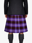 Person wearing a black coat and purple plaid kilt on a white background