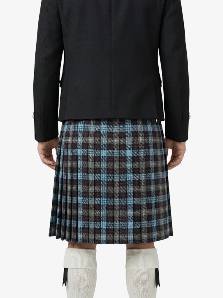Person wearing a black jacket and plaid kilt on a white background