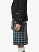 Person wearing a black blazer and plaid kilt on a white background