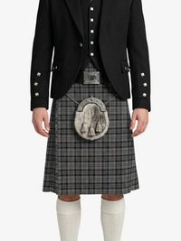 Person wearing a black jacket and gray plaid kilt with a tartan emblem on a white background